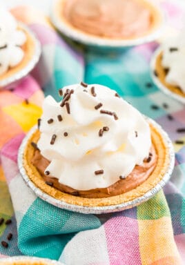 Mini No Bake Chocolate Cheesecake with whipped cream and chocolate sprinkles on a colorful checkered napkin.