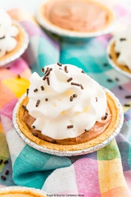 Mini No Bake Chocolate Cheesecake with whipped cream and chocolate sprinkles on a colorful checkered napkin.