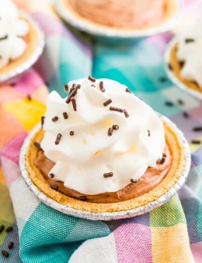 Mini No Bake Chocolate Cheesecake with whipped cream and chocolate sprinkles on a colorful checkered napkin.