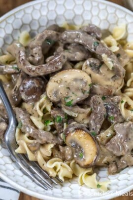 Beef stroganoff in a bowl with a fork garnished with pepper and parsley