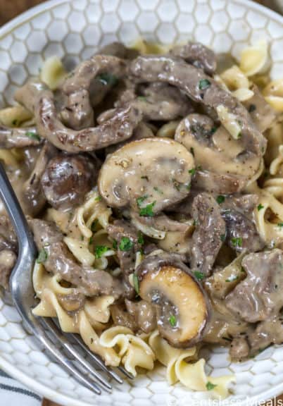Beef stroganoff in a bowl with a fork garnished with pepper and parsley