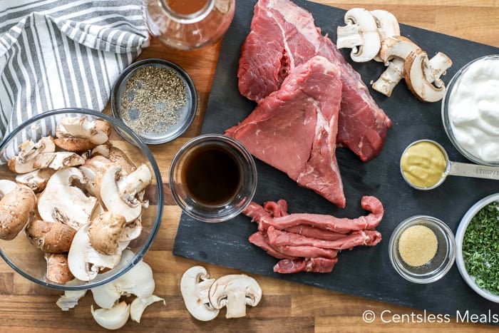 Ingredients for beef stroganoff on a cutting board and on a wooden board