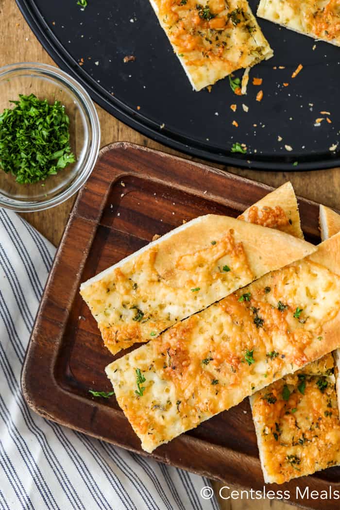 Pizza dough breadsticks on a pizza sheet and on a wooden board garnish with parsley