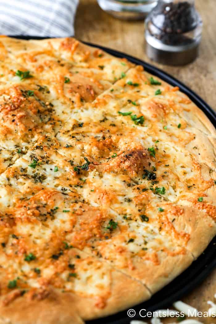 Pizza dough breadsticks on a pizza sheet garnished with parsley