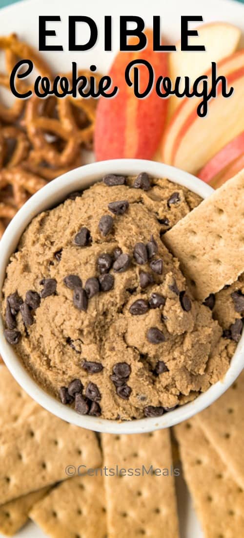 Edible cookie dough in a bowl with fruit and crackers on the side with writing