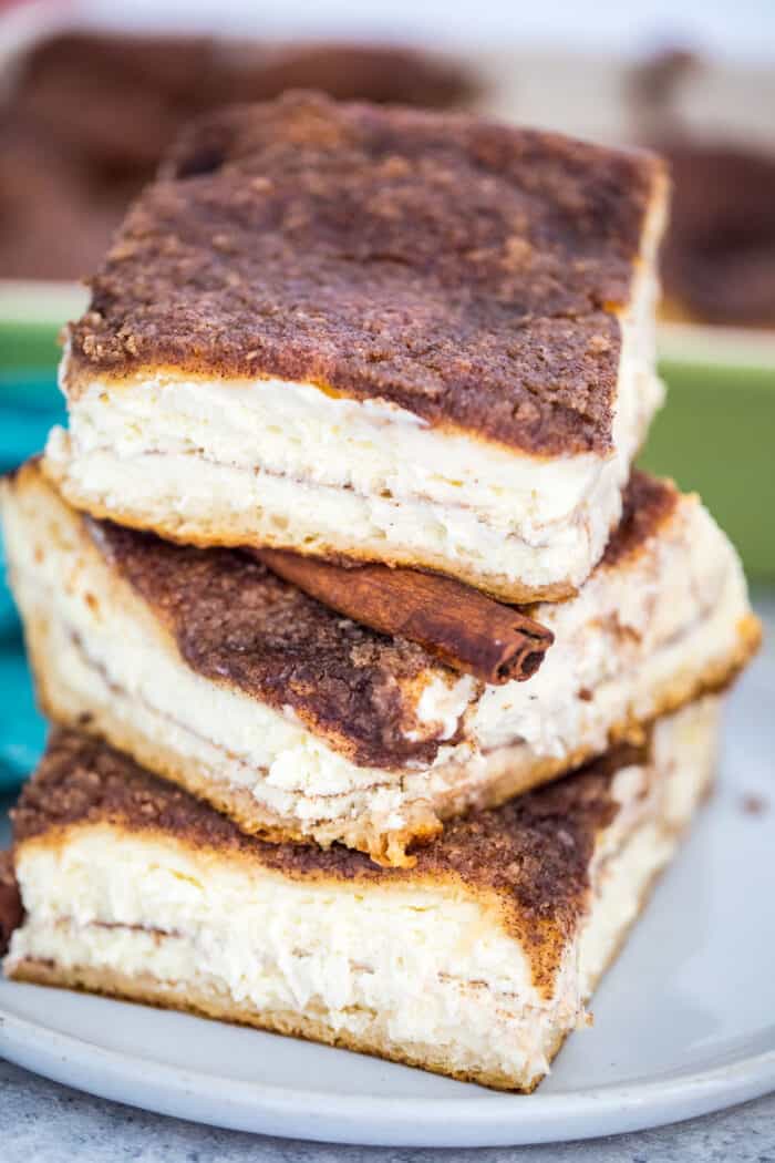 Stack of Sopapilla Cheesecake on a plate with a cinnamon stick