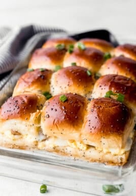 Breakfast sandwiches in a clear casserole dish with green onions on top