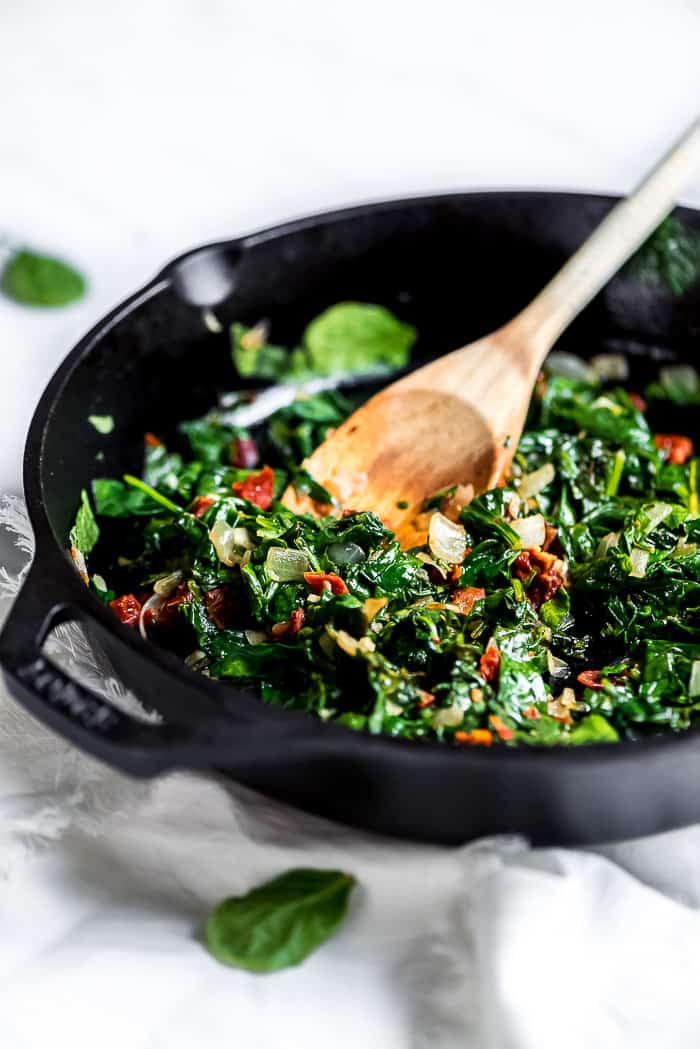 Spinach frittata ingredients in a pan with a wooden spoon