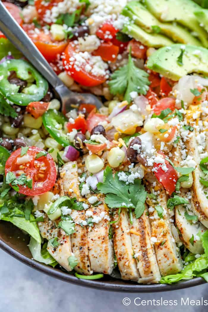 Chicken burrito bowl with a fork and topped with cheese