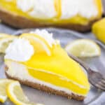 Piece of lemon cheesecake on a plate with a fork and lemon slices