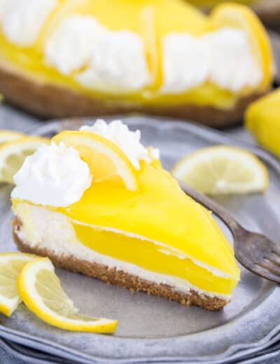 Piece of lemon cheesecake on a plate with a fork and lemon slices