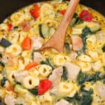 Chicken Tortellini Soup in a pot with a wooden spoon