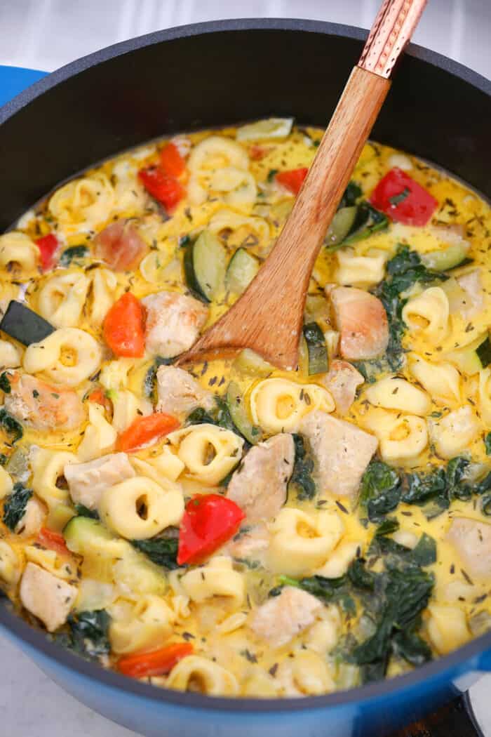 Chicken Tortellini Soup in a pot with a wooden spoon