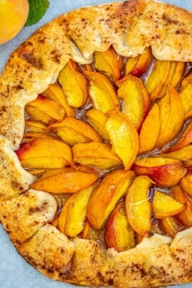 Peach Galette on a marble board with a peach on the side