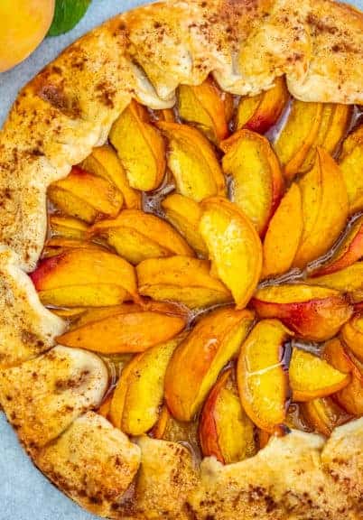 Peach Galette on a marble board with a peach on the side