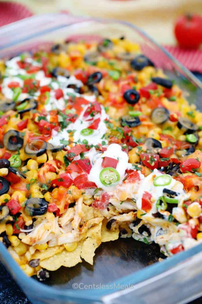 Chicken nachos in a casserole dish with sour cream on top