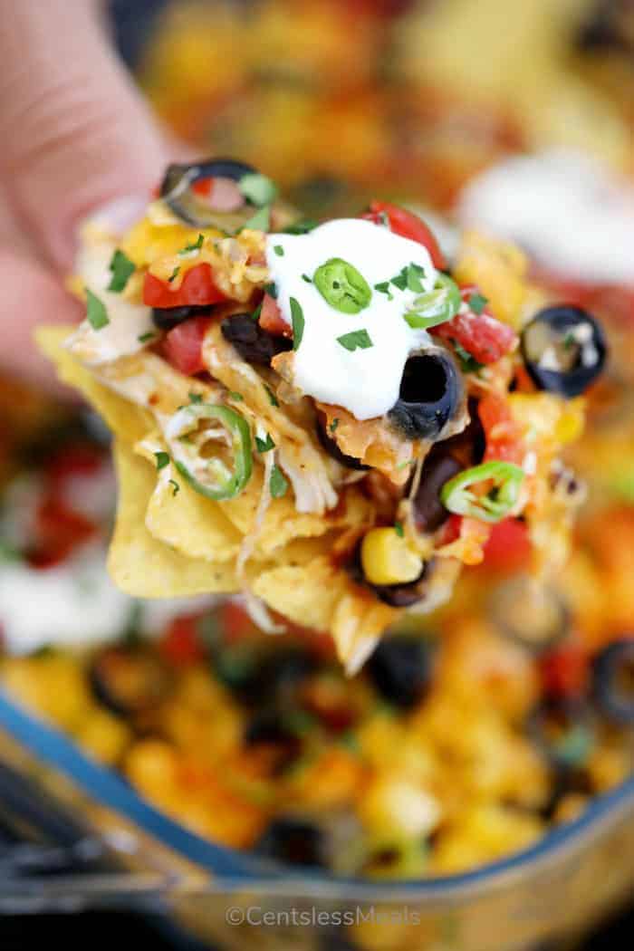 Bite of chicken nachos with sour cream and jalapenos