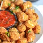 Crispy fried tortellini on a white plate with marinara sauce