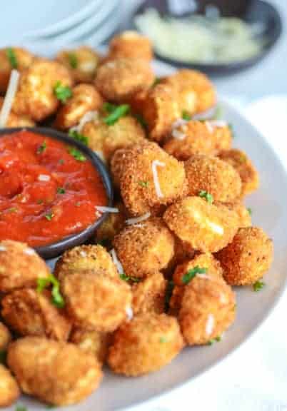 Crispy fried tortellini on a white plate with marinara sauce