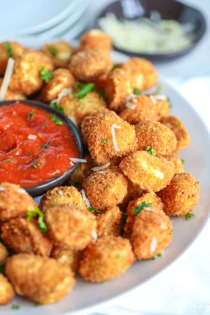 Crispy fried tortellini on a white plate with marinara sauce