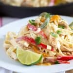 Fajita pasta on a white plate with a lime wedge