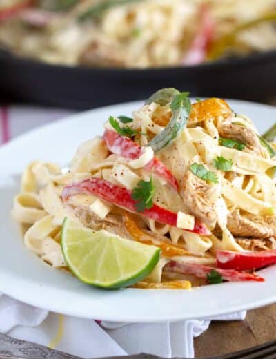 Fajita pasta on a white plate with a lime wedge