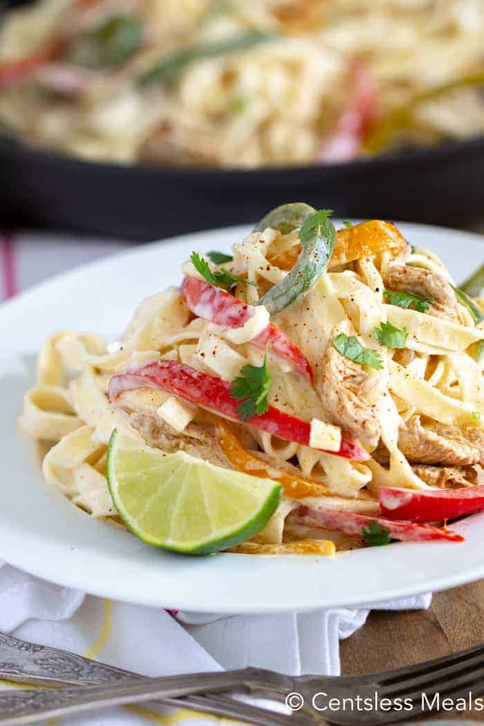 Fajita pasta on a white plate with a lime wedge