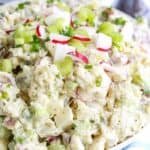 Creamy potato salad in a white bowl garnished with radishes and celery
