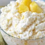 Pineapple rice pudding in a clear bowl with pieces of pineapple as garnish