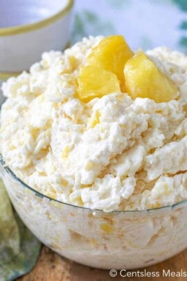 Pineapple rice pudding in a clear bowl with pieces of pineapple as garnish
