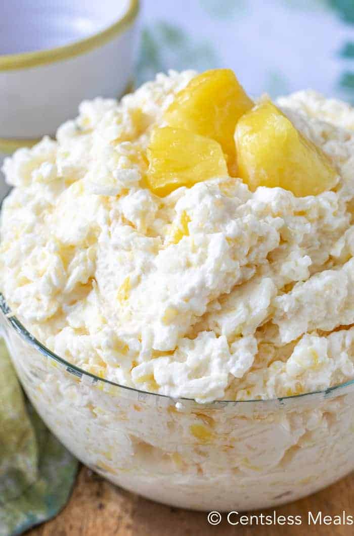 Pineapple rice pudding in a clear bowl with pieces of pineapple as garnish