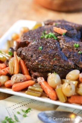 Slow cooker pot roast on a plate with veggies and parsley