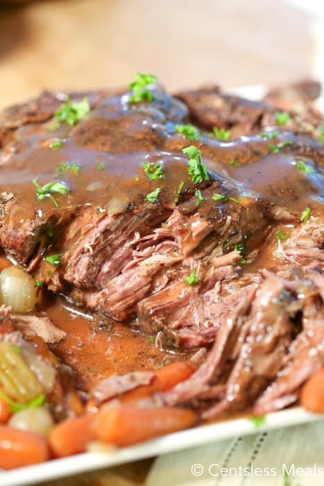 Slow cooker pot roast on a plate with gravy and veggies