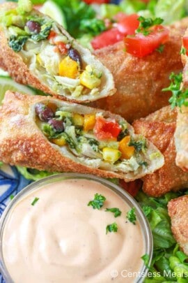 Avocado egg rolls on a plate with dip in a glass bowl
