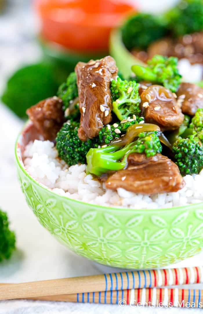 Crockpot beef and broccoli in a bowl with rice and garnished with sesame seeds