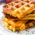 Mac and cheese waffles on a plate garnish with parsley with Bob Evans mac and cheese in the background