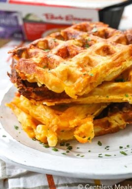 Mac and cheese waffles on a plate garnish with parsley with Bob Evans mac and cheese in the background