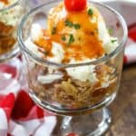 Pulled pork sundae in a glass dish garnished with parsley and a cherry tomato