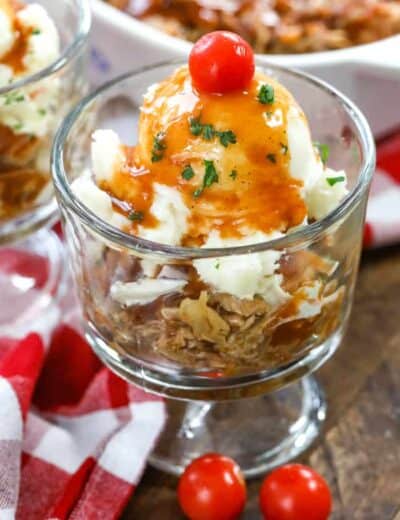 Pulled pork sundae in a glass dish garnished with parsley and a cherry tomato