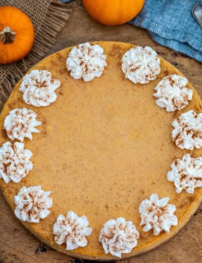 Pumpkin cheesecake with whipped cream on a wooden board