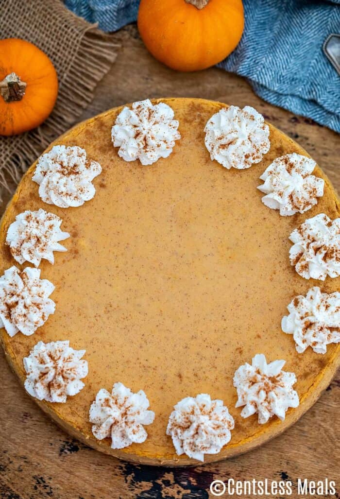 Pumpkin cheesecake with whipped cream on a wooden board