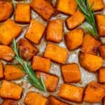 Roasted butternut squash on a baking sheet with rosemary Sprigs