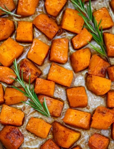 Roasted butternut squash on a baking sheet with rosemary Sprigs
