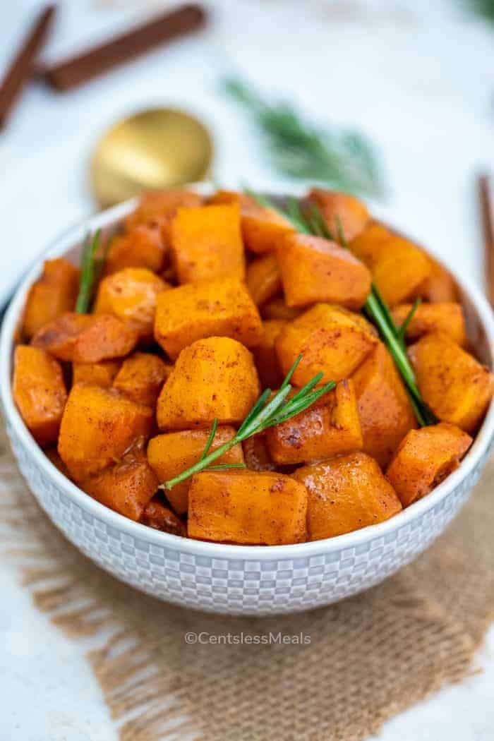 Roasted butternut squash in a white bowl with rosemary