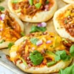 Pulled pork mini pizzas on a baking sheet garnished with cilantro