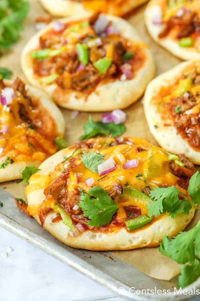 Pulled pork mini pizzas on a baking sheet garnished with cilantro