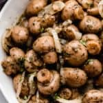 marinated mushrooms in a white bowl with onion and parsley