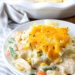 Turkey pot pie on a white plate with a pie dish in the background