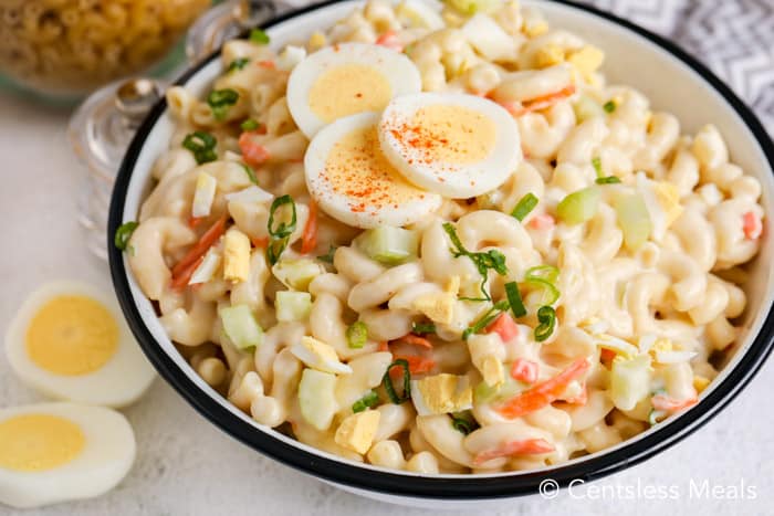 Macaroni salad with egg in a bowl garnished with green onion and slices of hard-boiled egg