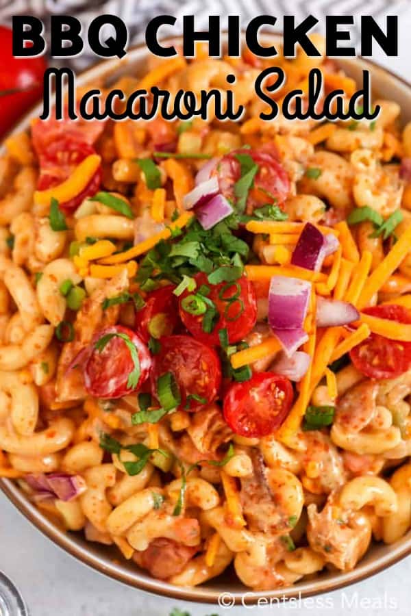 Barbecue chicken macaroni salad in a bowl garnished with tomatoes onions and cheese with writing
